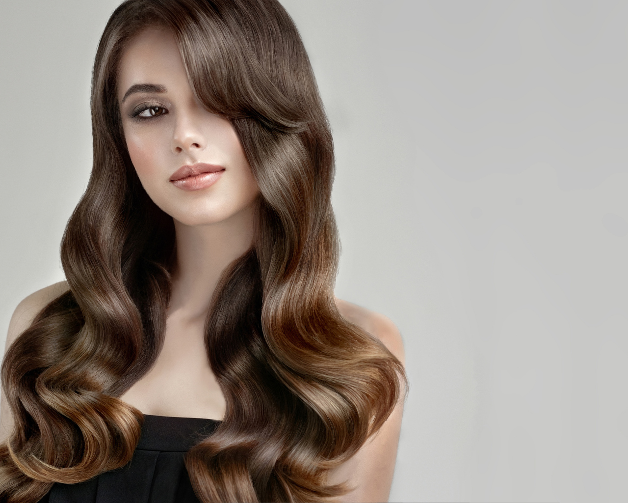 Молодая девушка с красивыми длинными волосами на сером фоне
