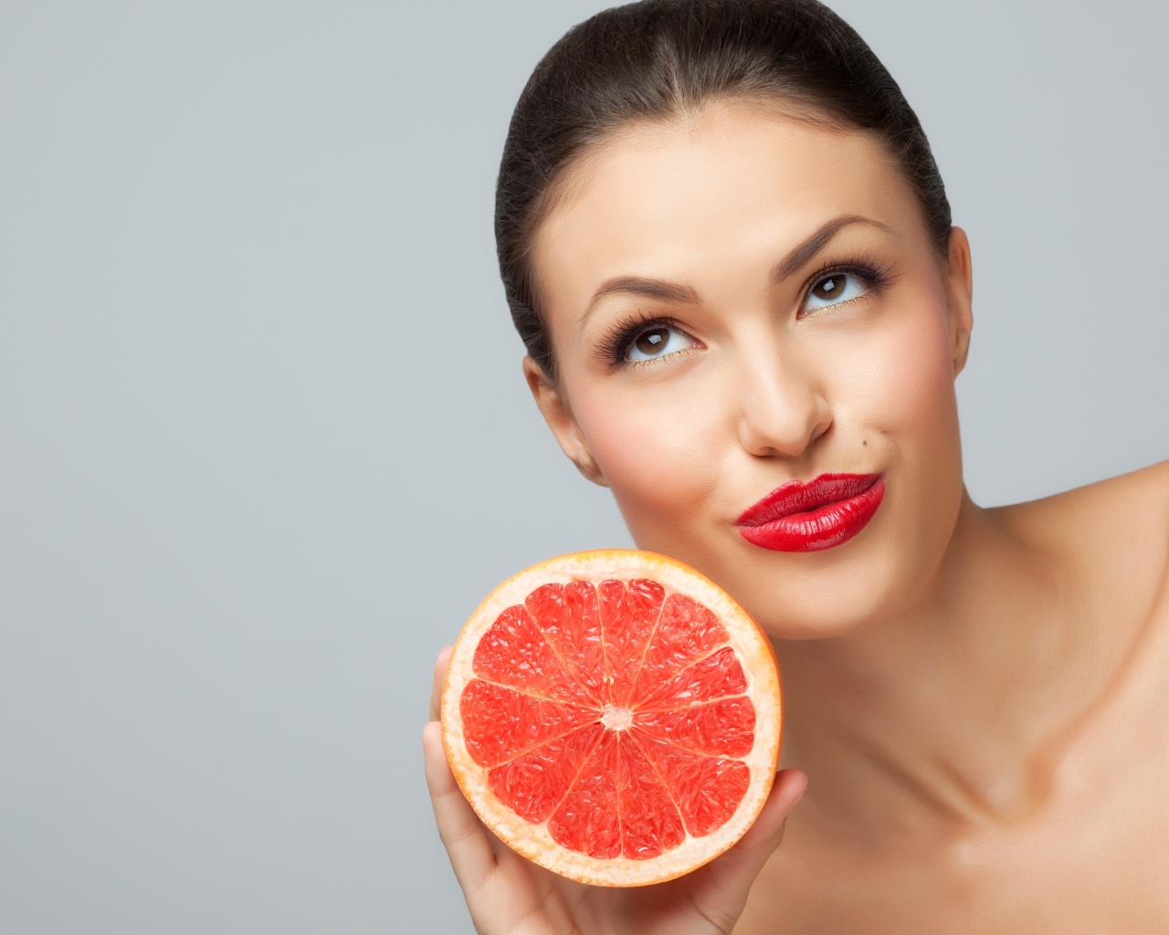 Молодая девушка с красными губами с половиной грейпфрута