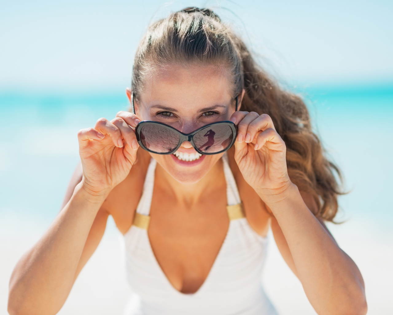 Молодая улыбающаяся девушка в солнечных очках 