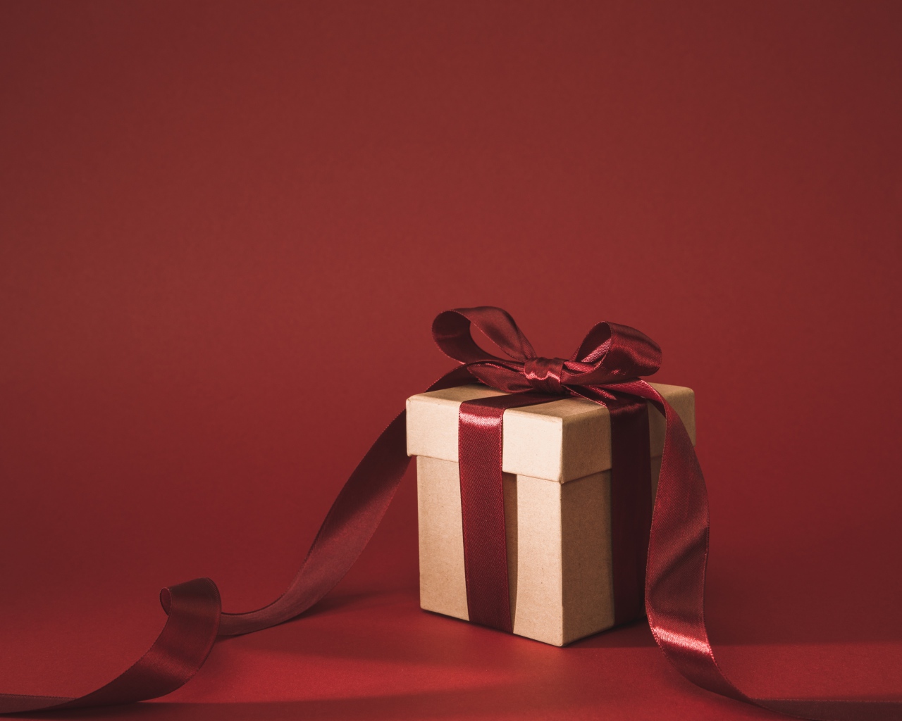 Gift box with red bow on red background