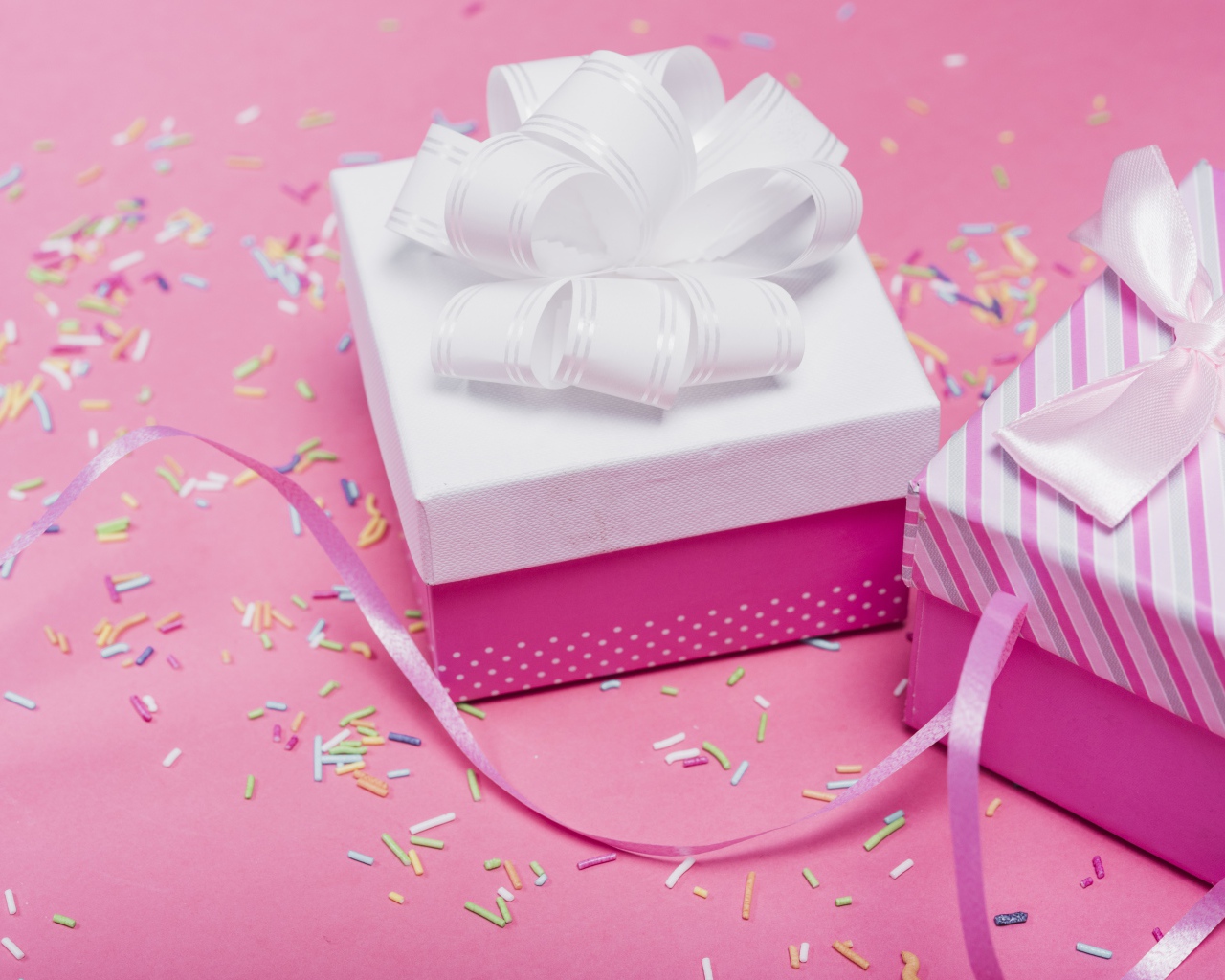 Two gift boxes with bows on a pink background