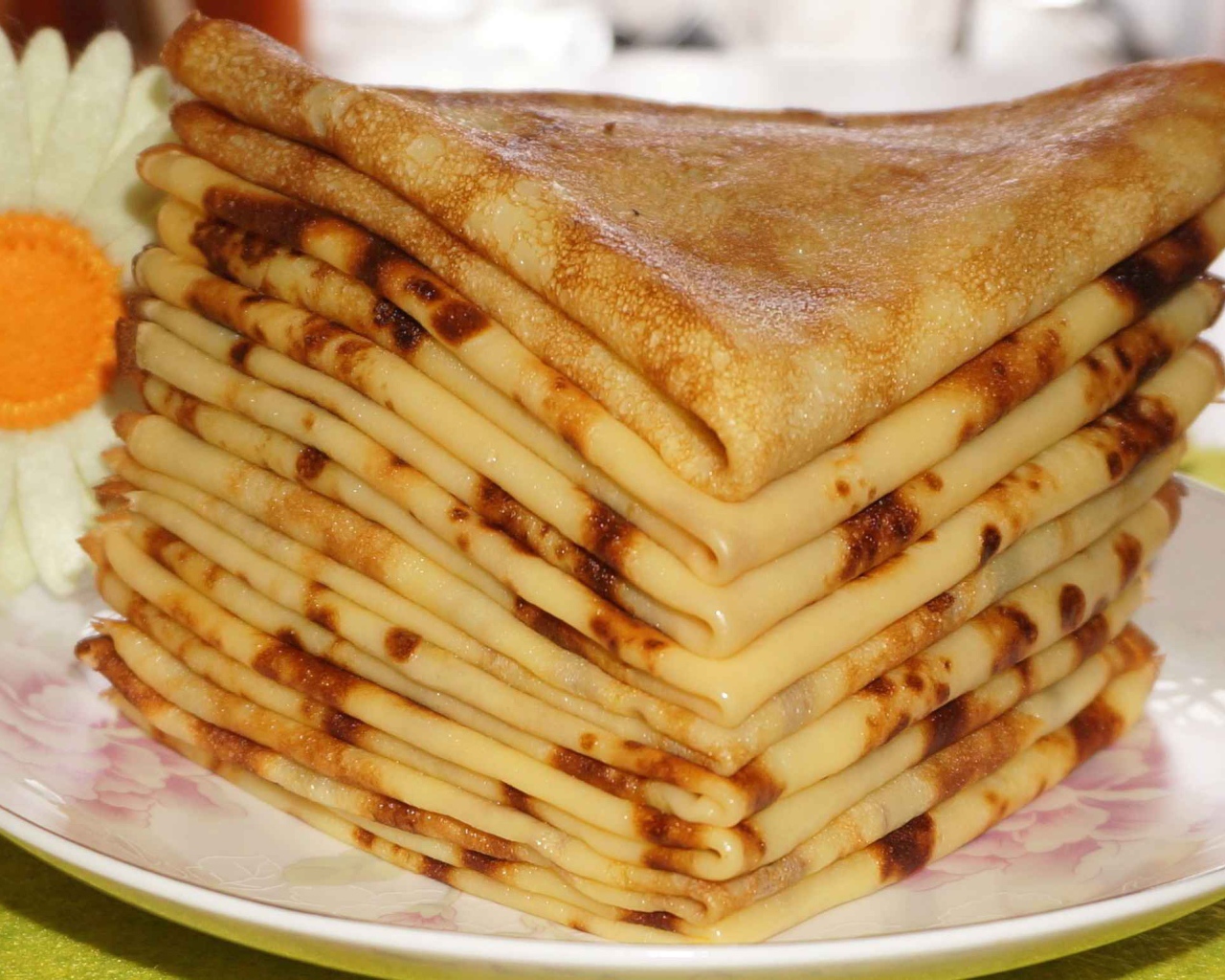 Стопка тонких блинов с ромашкой на Масленицу