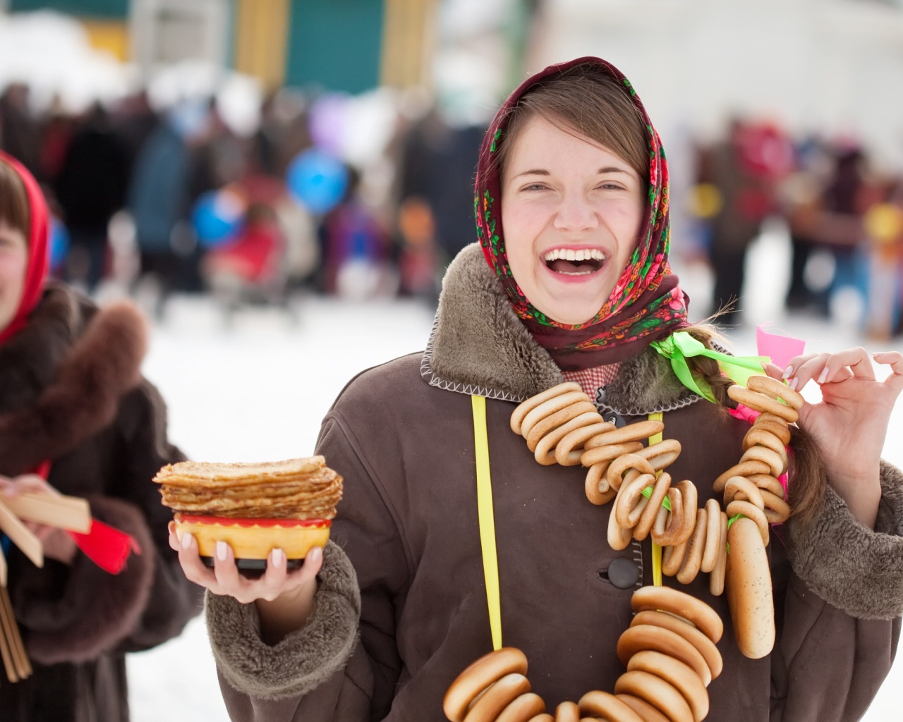 Улыбающаяся девушка с угощениями на праздник Масленица 2018