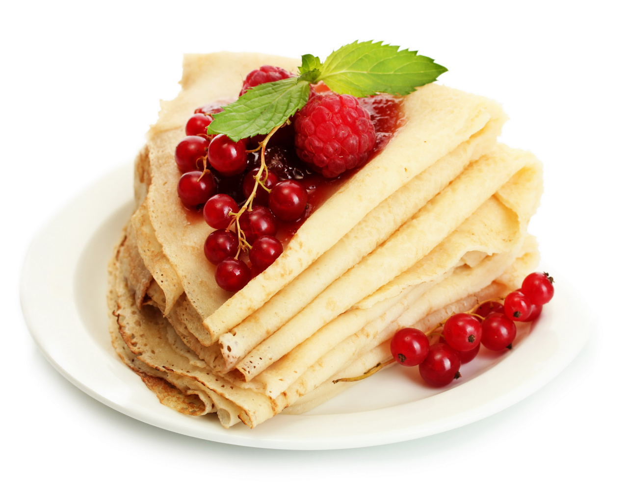 Тонкие блины с малиной и красной смородиной на белом фоне на Масленицу