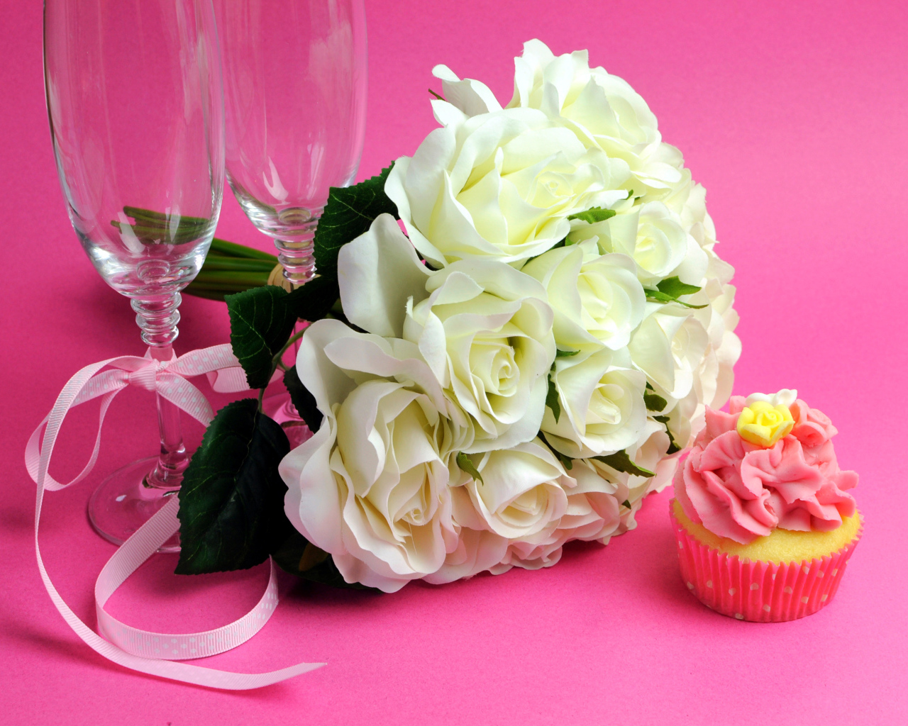 Букет белых роз, пирожное и два бокала на розовом фоне на 8 марта