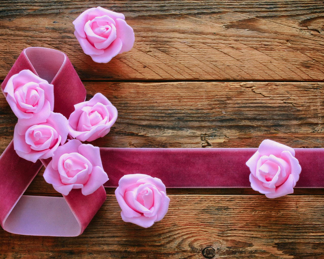 Восьмерка из ленты с розовыми розами на деревянном фоне на Международный женский день
