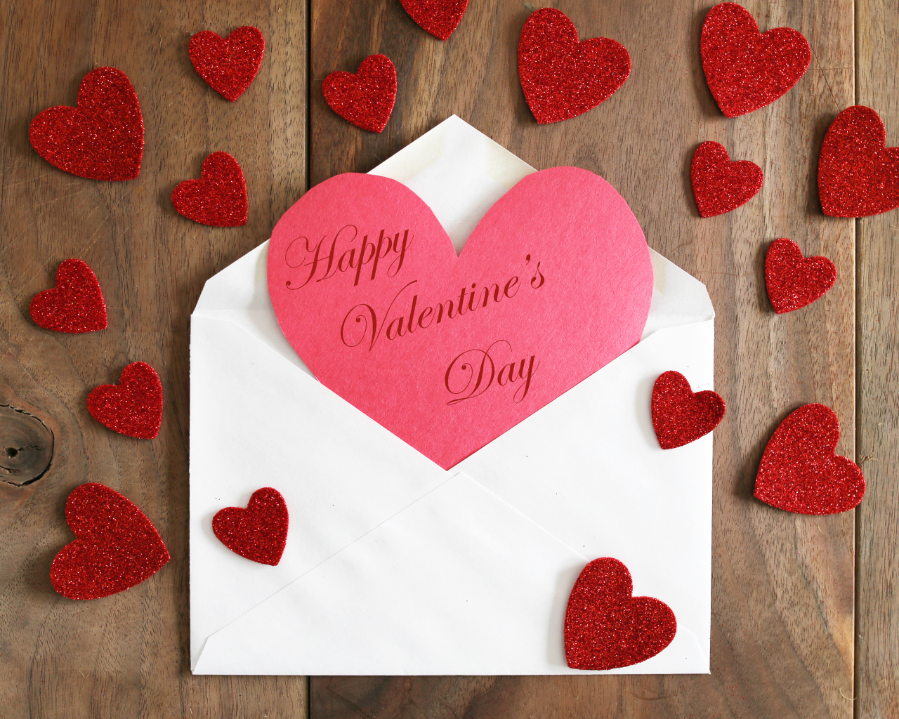 Белый конверт с валентинкой на деревянном столе с красными сердечками на 14 февраля