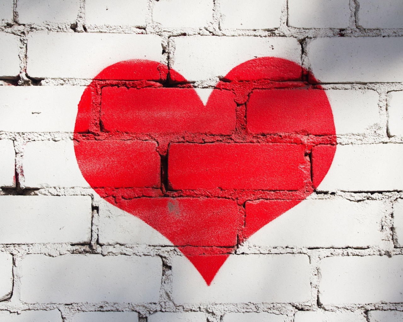 Большое красное сердце нарисовано на кирпичной стене