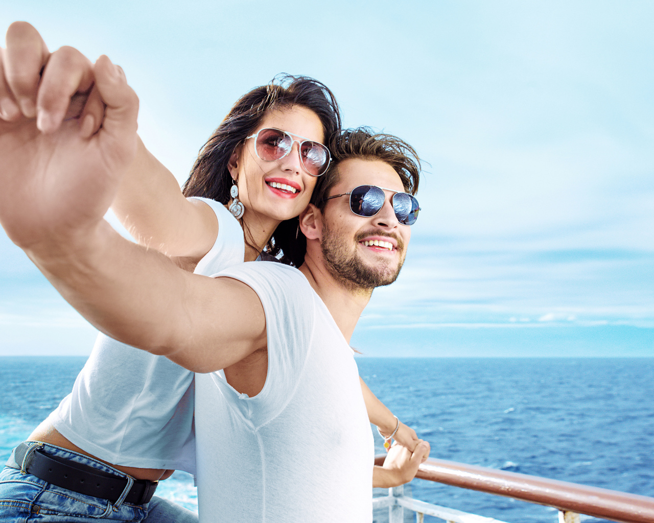 Влюбленная пара держится за руки на фоне моря