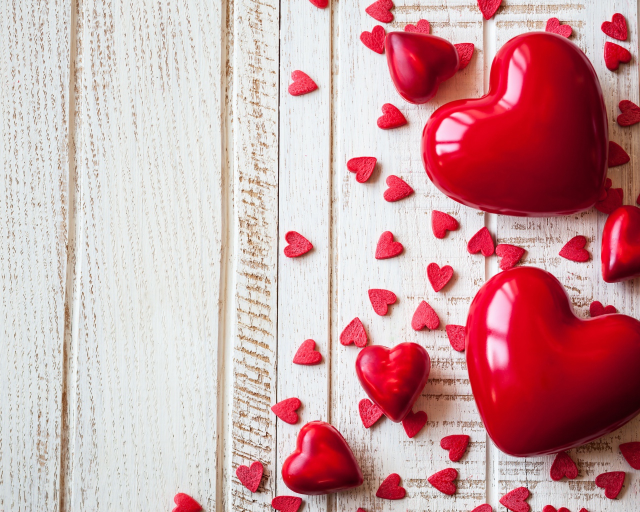 Большие и маленькие  красные  сердечки на деревянном фоне
