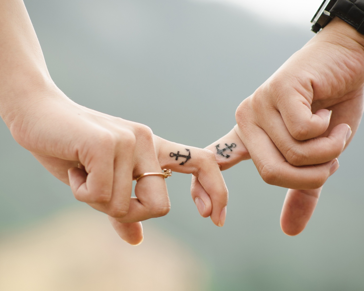 Hands of a loving couple with tattoos on their hands.