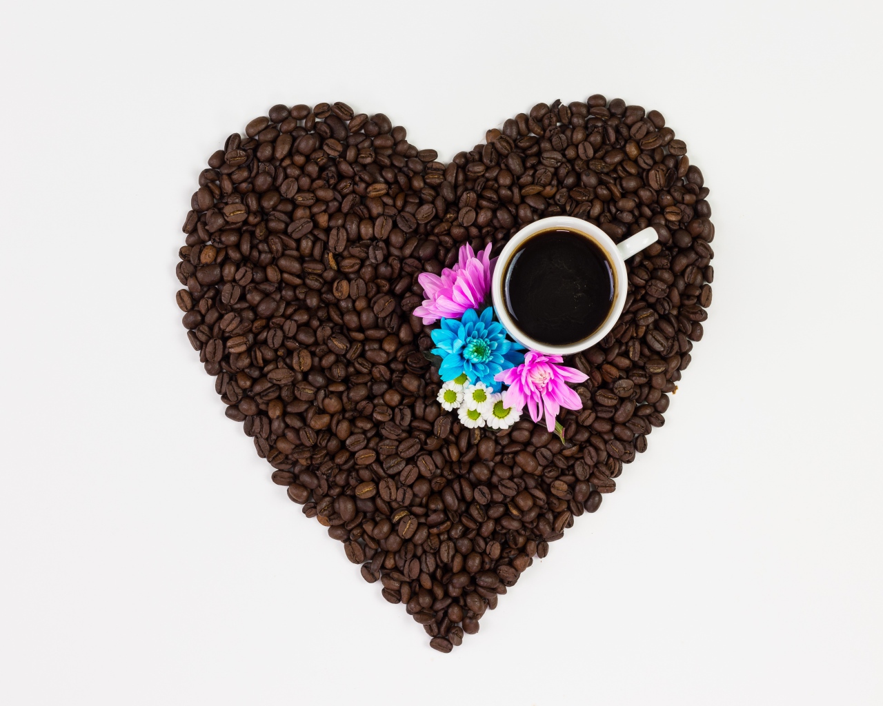 Сердце из кофейных зерен с чашкой на белом фоне