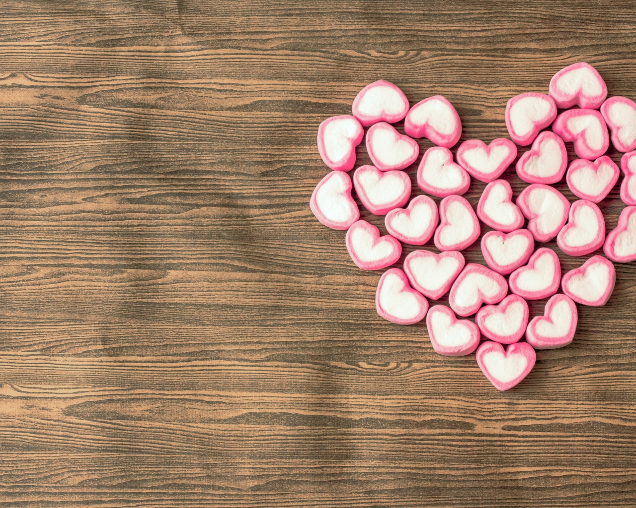 Сердце из конфет в форме сердца на деревянном столе