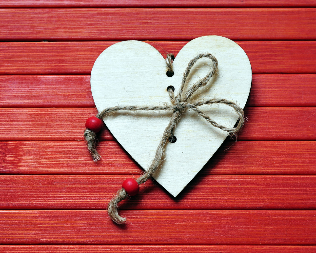Сердце с веревкой на красном деревянном фоне