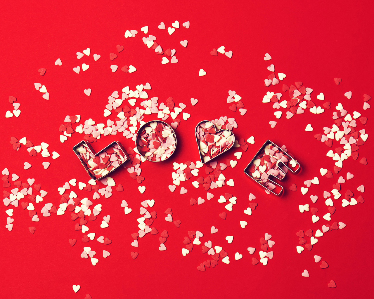 Надпись любовь из маленьких  сердечек на красном фоне