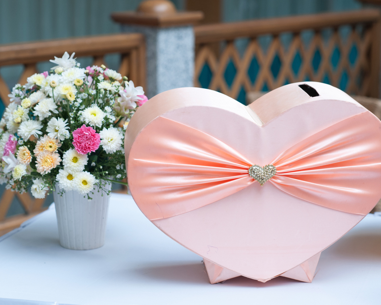 Большая розовая коробка в форме сердца на столе с букетом хризантем