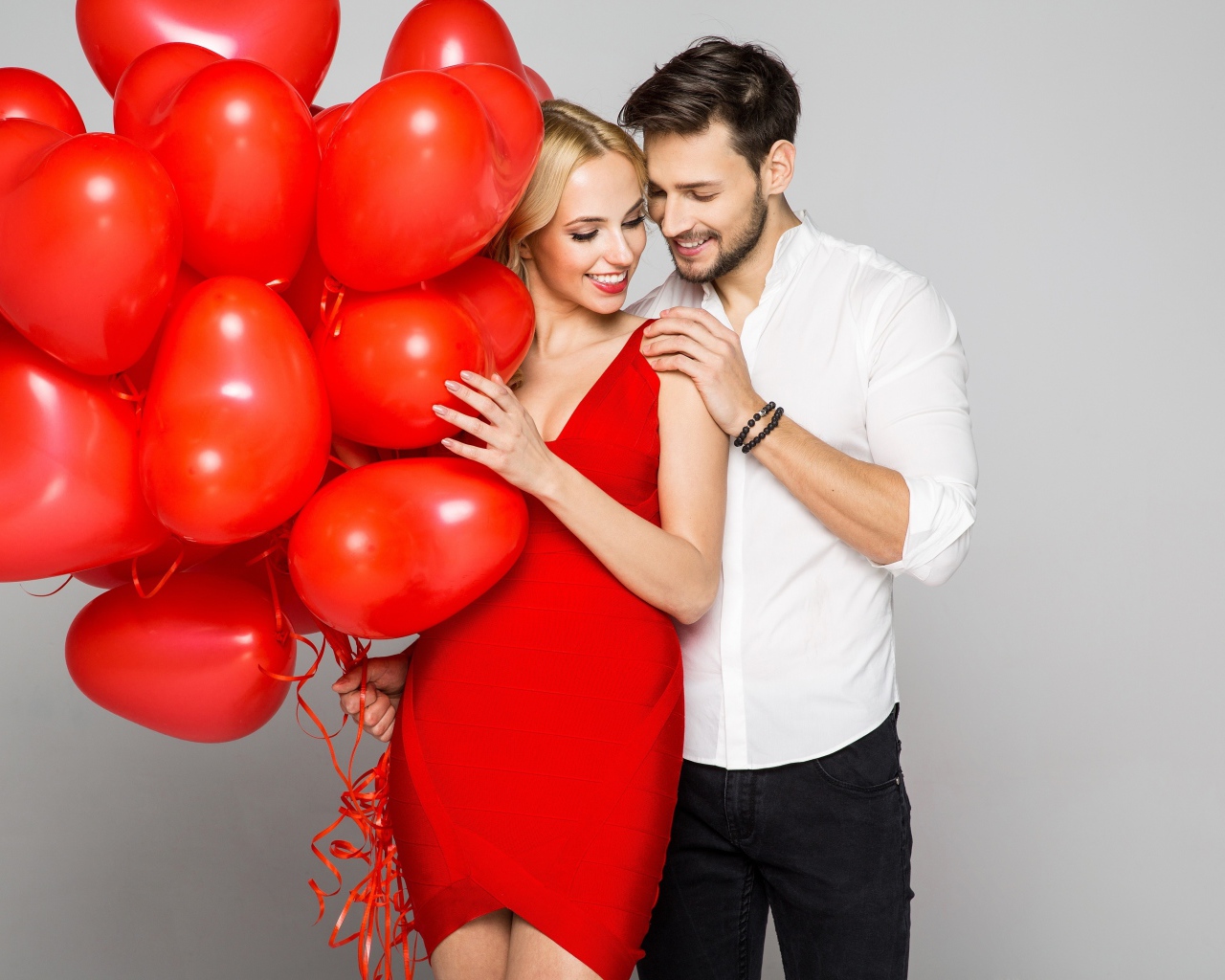 Влюбленная пара с красными воздушными шарами в форме сердца