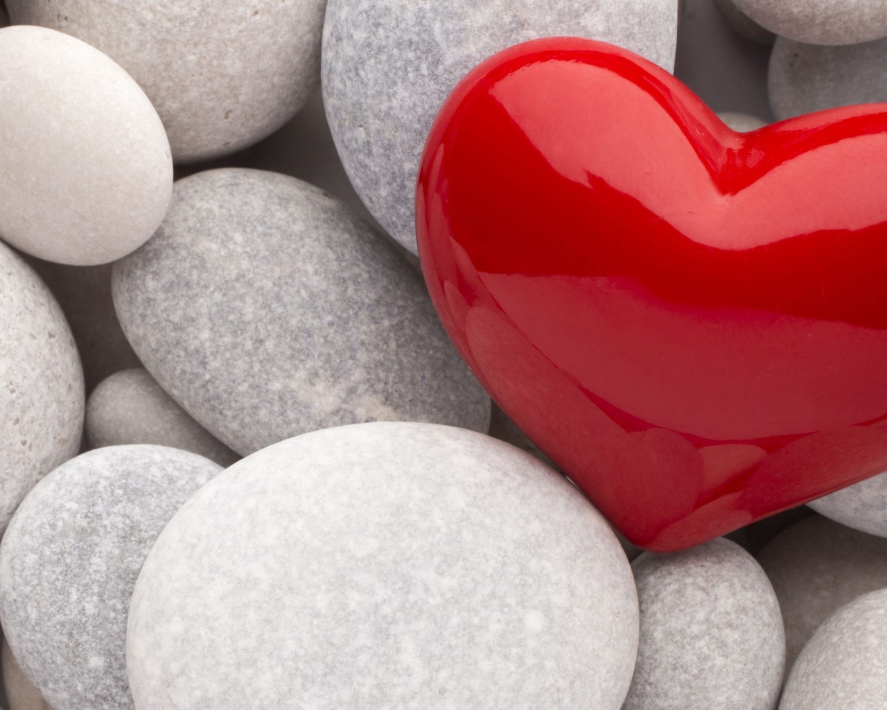 Красное сердце лежит на серых камнях 