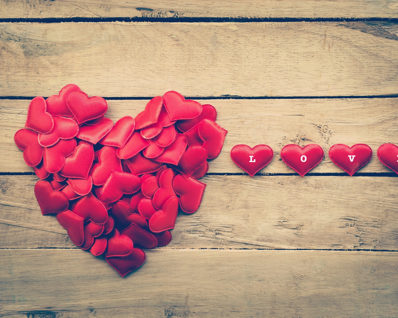 Маленькие красные сердечки на деревянной поверхности 