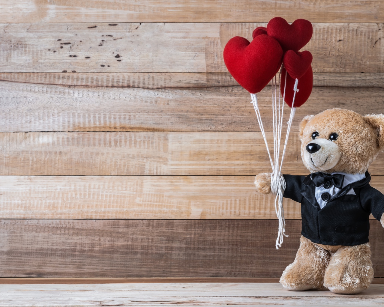 Плюшевый медведь с сердечками на деревянном фоне