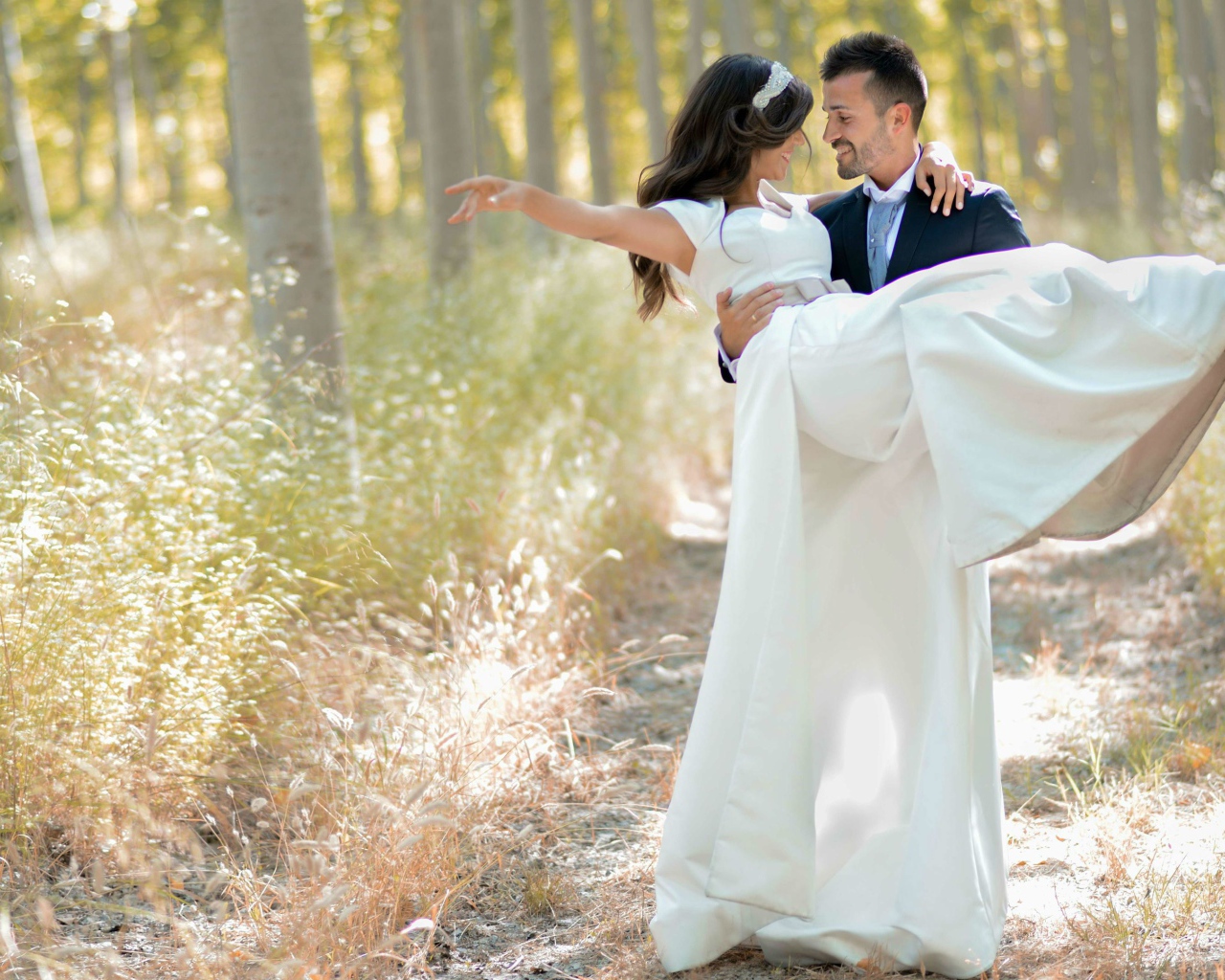 Парень жених держит на руках невесту в белом платье