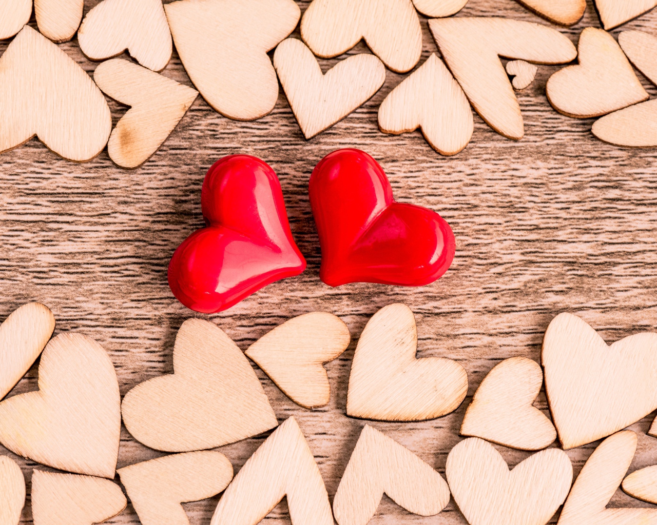 Два красных сердечка на столе с деревянными сердечками