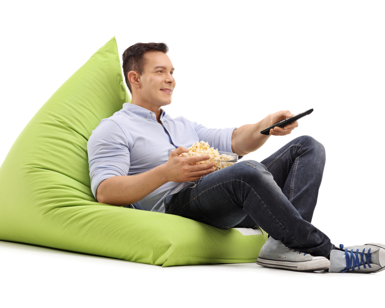 A man with popcorn and a TV remote is lying on a green pillow