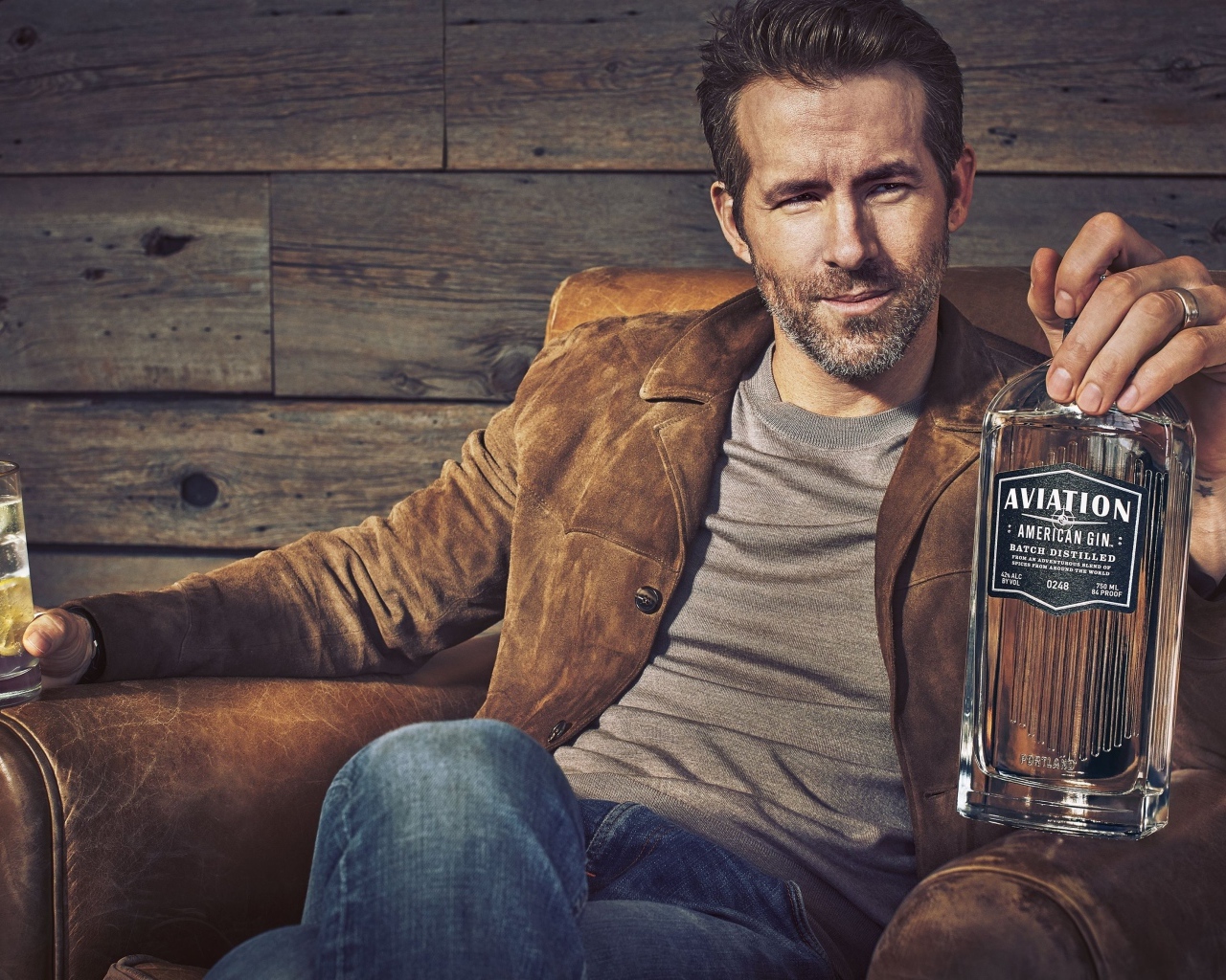 Актер Райан Рейнольдс в кресле с бутылкой в руке