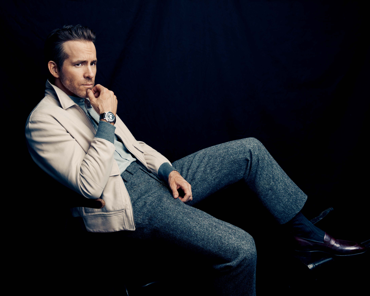 Актер Райан Рейнольдс сидит на стуле с часами на руке