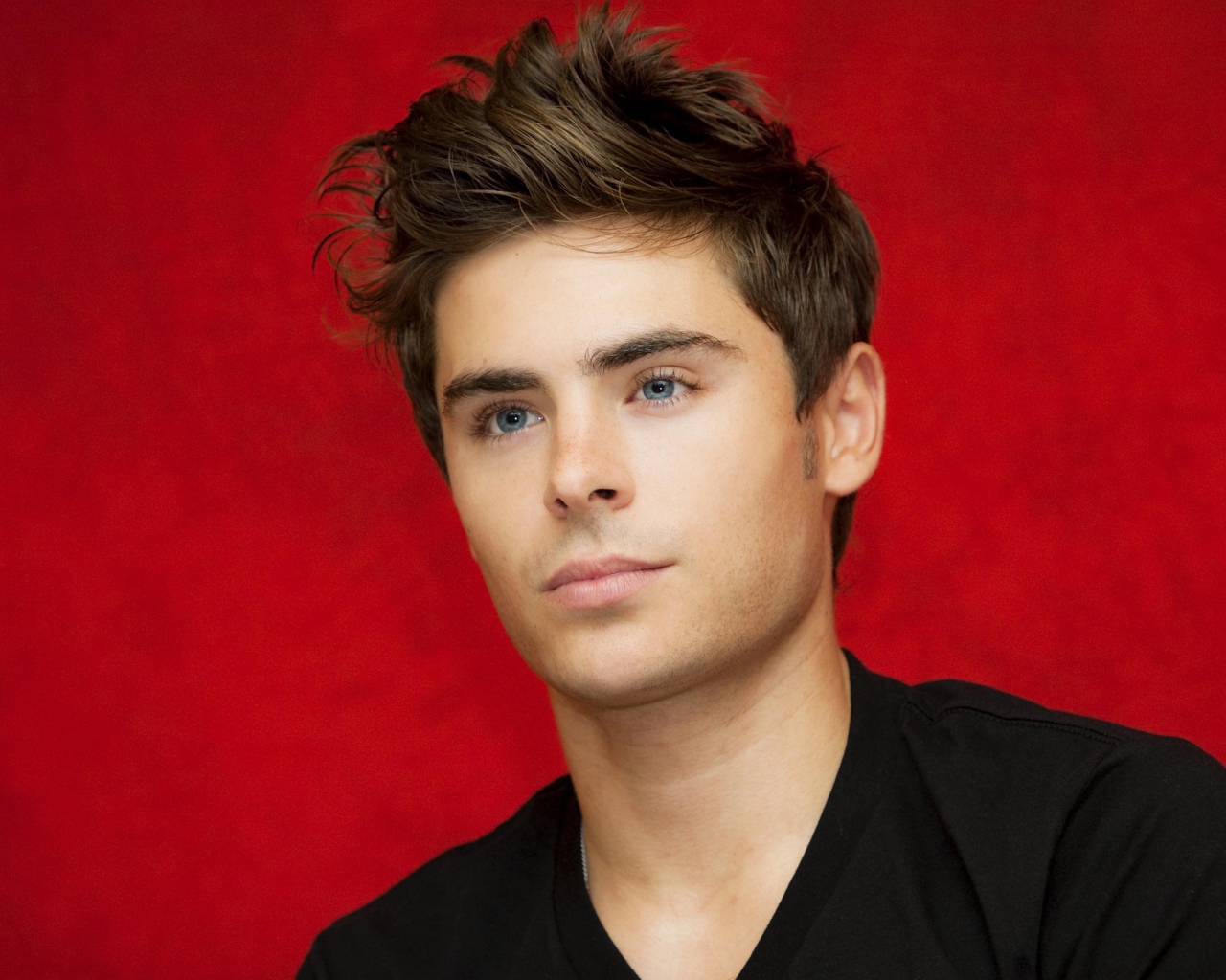 Голубоглазый актер Зак Эфрон на красном фоне