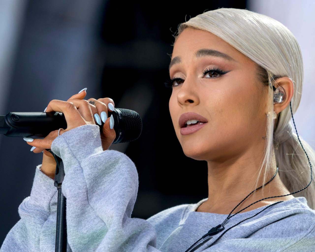 Светловолосая певица Ариана Гранде с микрофоном на сцене 