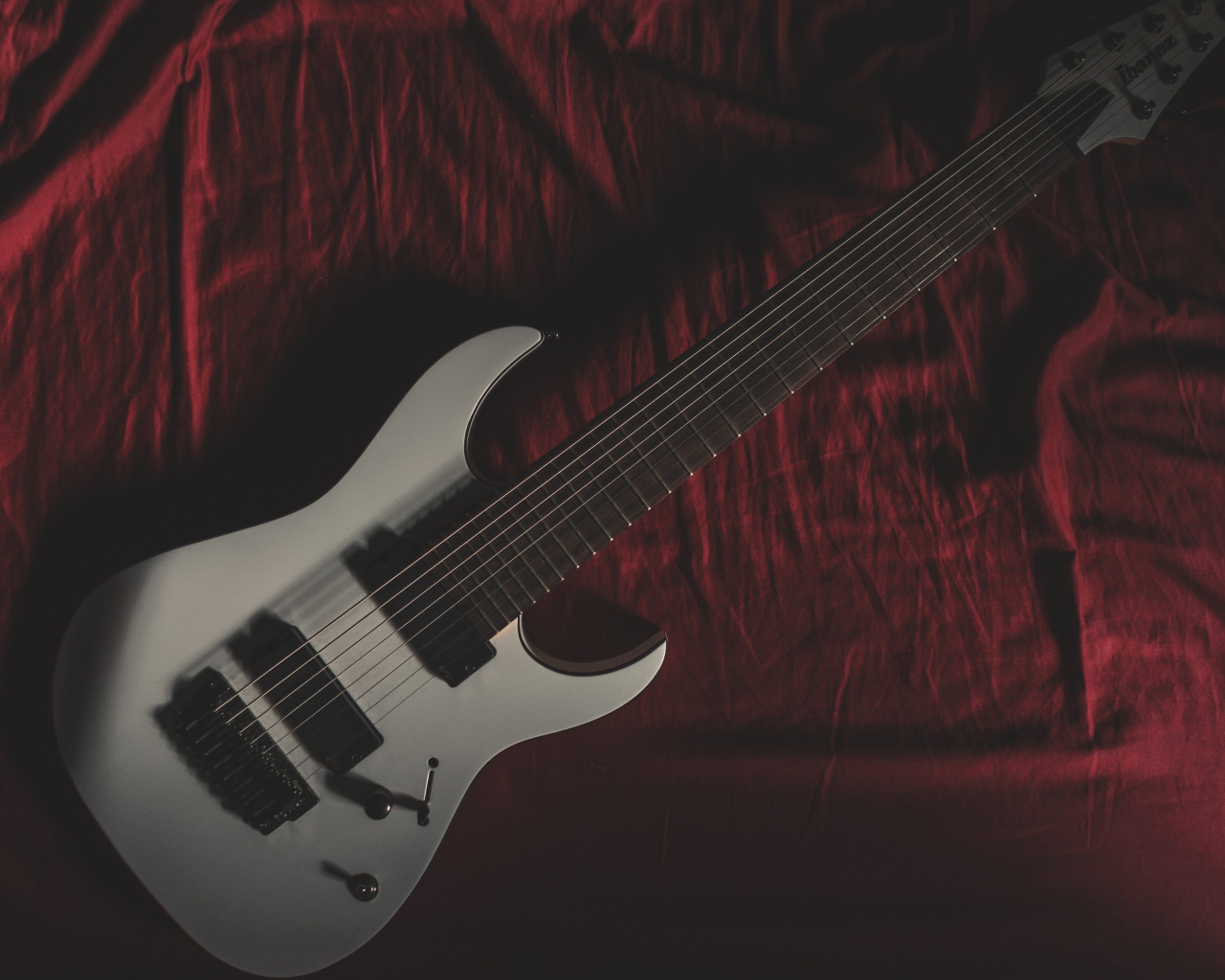 Гитара лежит на красном покрывале