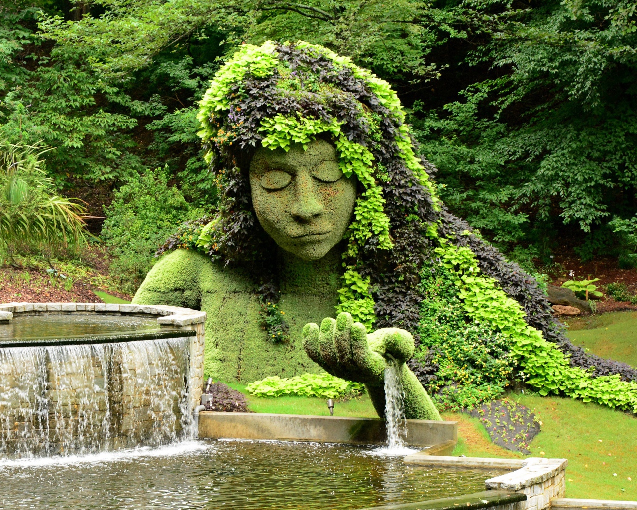 Красивый водопад в парке со скульптурой 