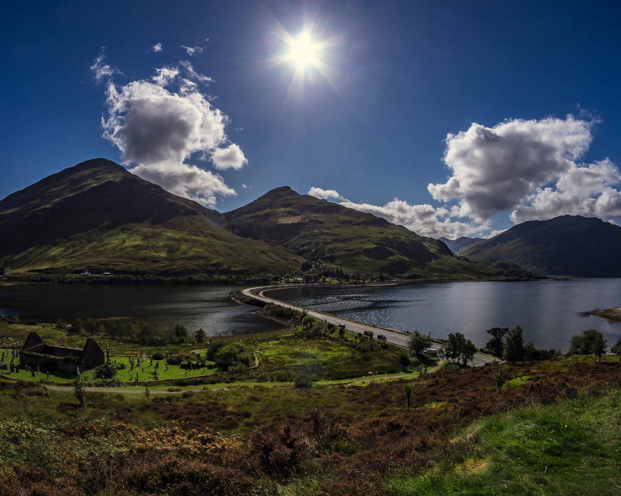 Яркое солнце в голубом небе над горами у реки