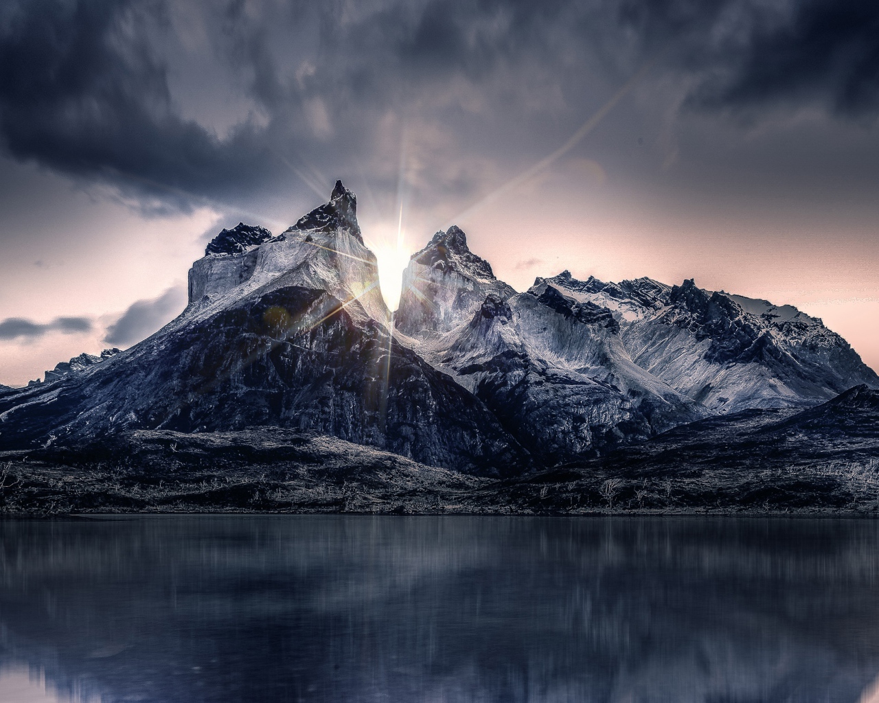 Рассвет солнца над горами у озера под пасмурным небом