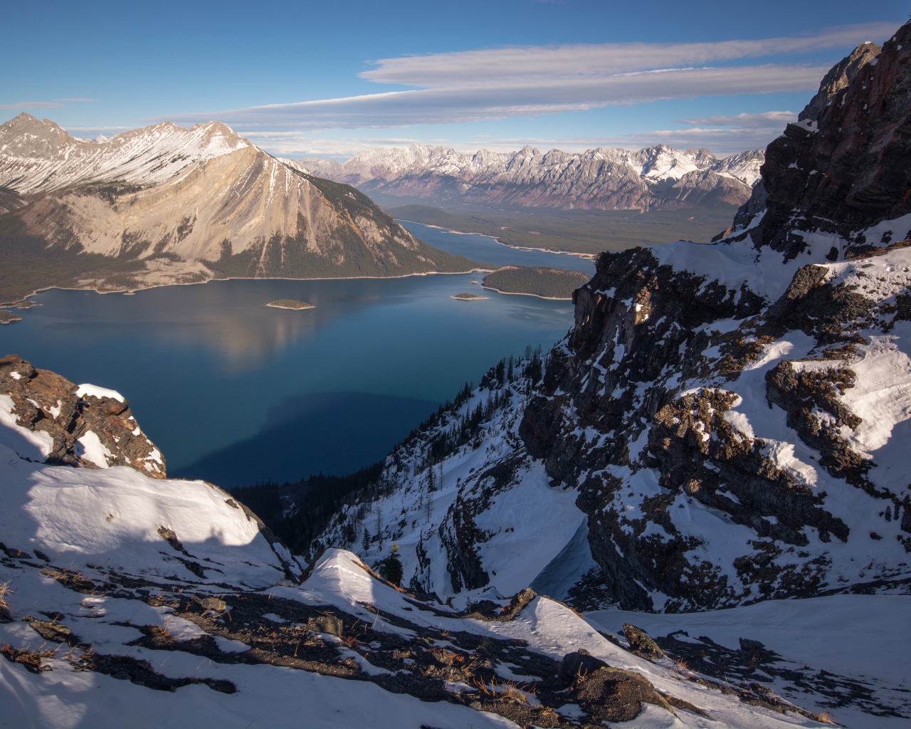 Озеро между заснеженных гор на фоне голубого неба