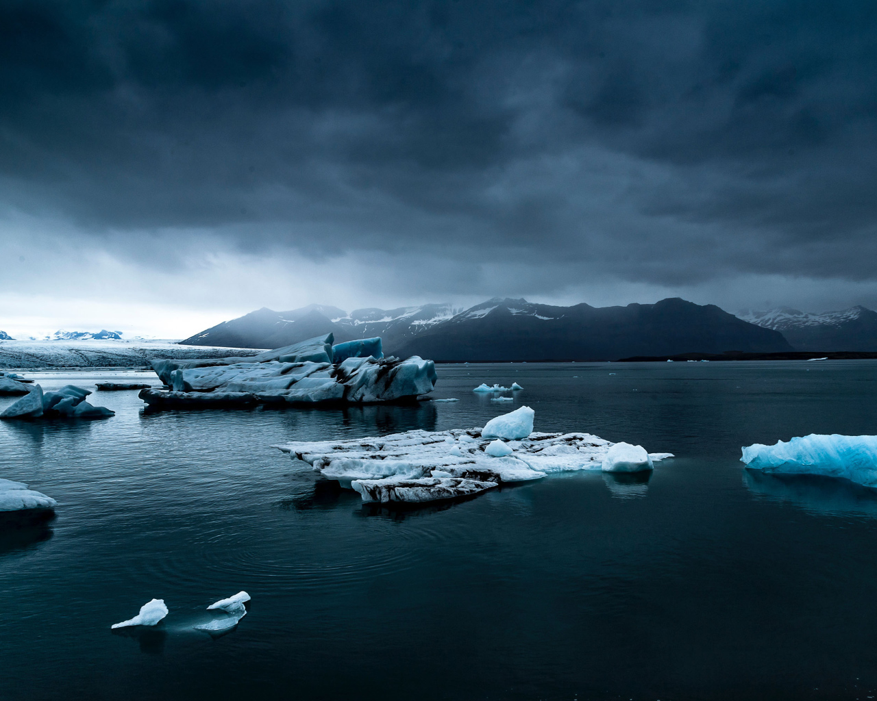 Large blue ice floes in the water under a cloudy sky
