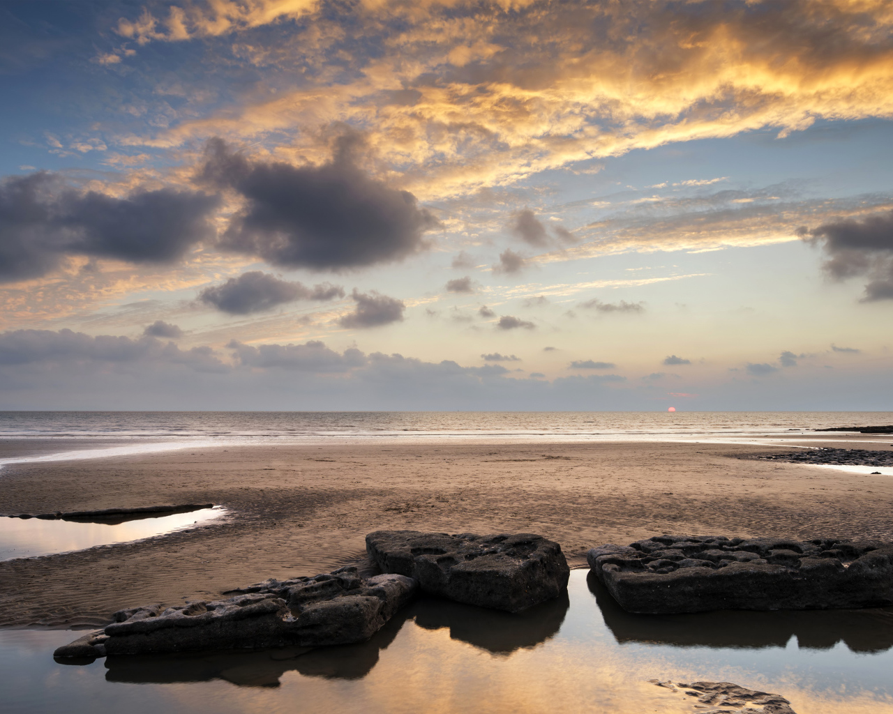 Большие камни в воде на песке под красивым небом