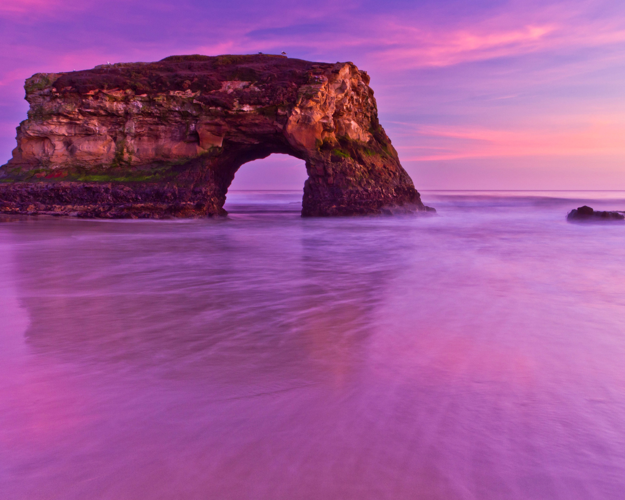 Гора с аркой в океане на фоне красивого неба