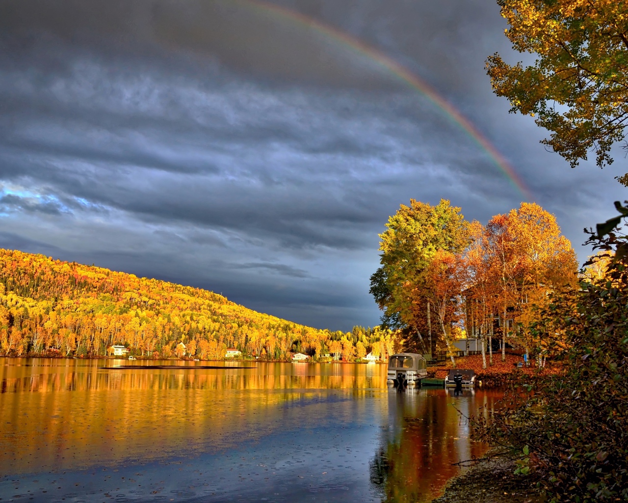 Радуга в пасмурном небе над озером у осеннего леса