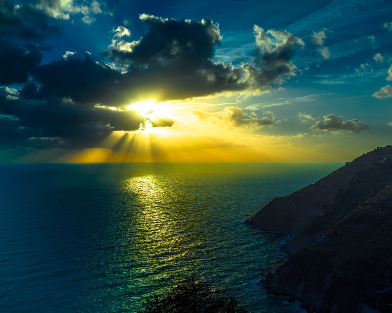 Лучи яркого солнца пробиваются сквозь облака над морем