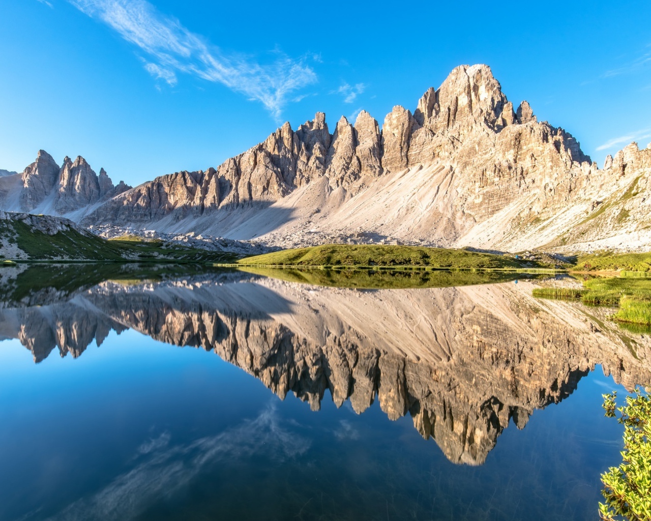 Горы и голубое небо отражаются в чистой воде 