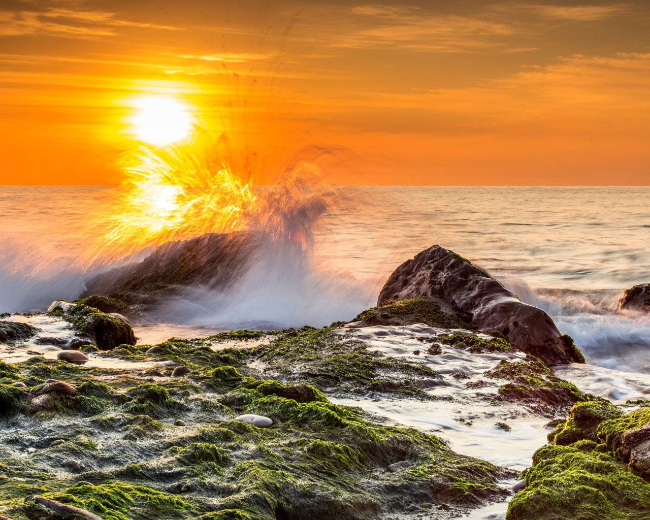 Бушующие волны в море бьются об камни на закате