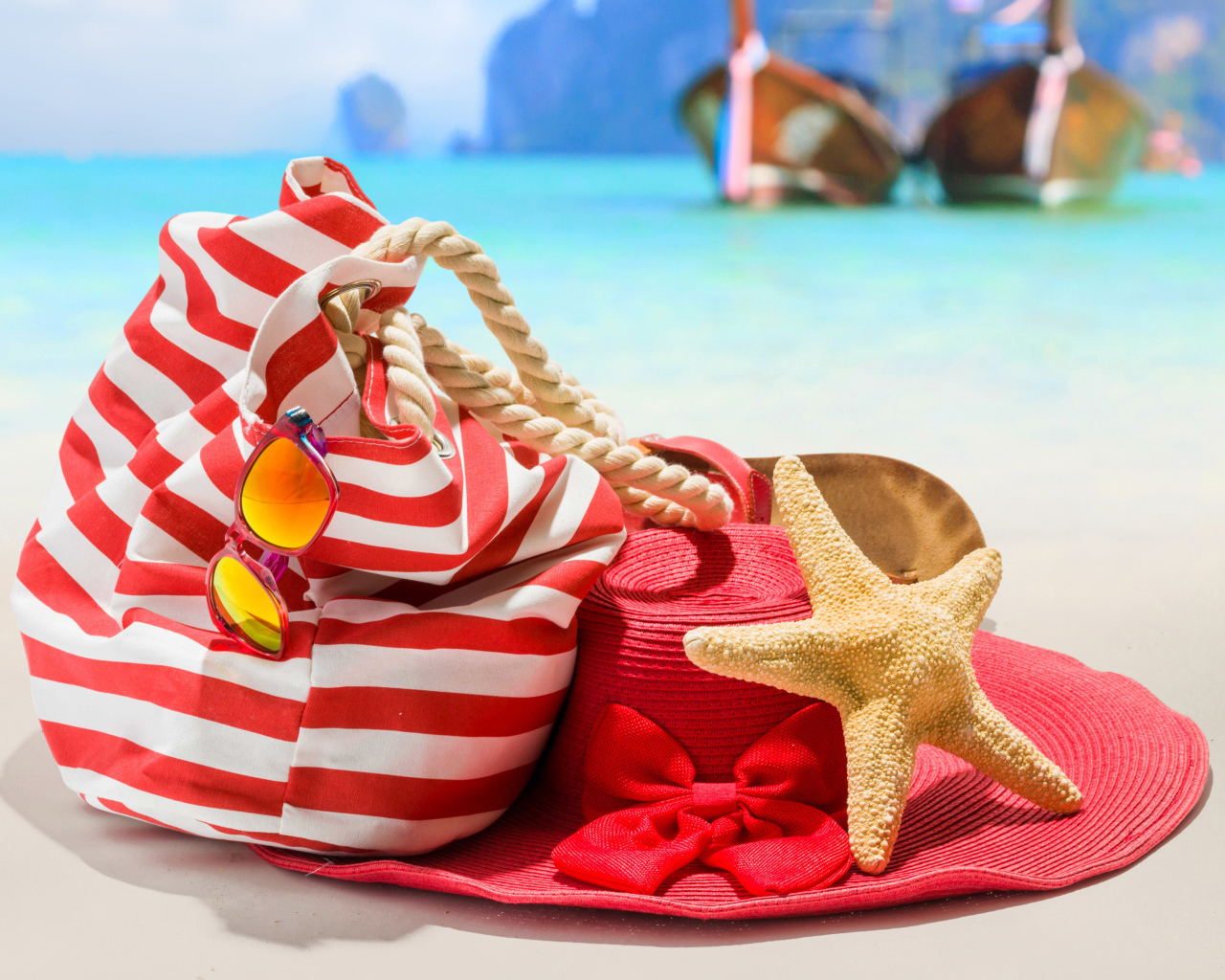 Большая красная шляпа с сумкой и морской звездой на пляже