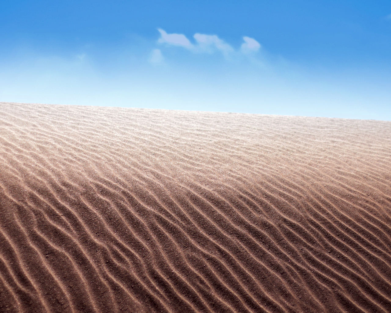 Песок в пустыне на фоне голубого неба