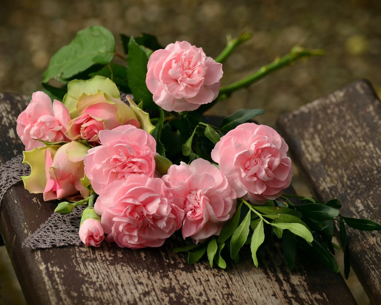 Букет красивых нежных розовых роз лежит на деревянной лавке