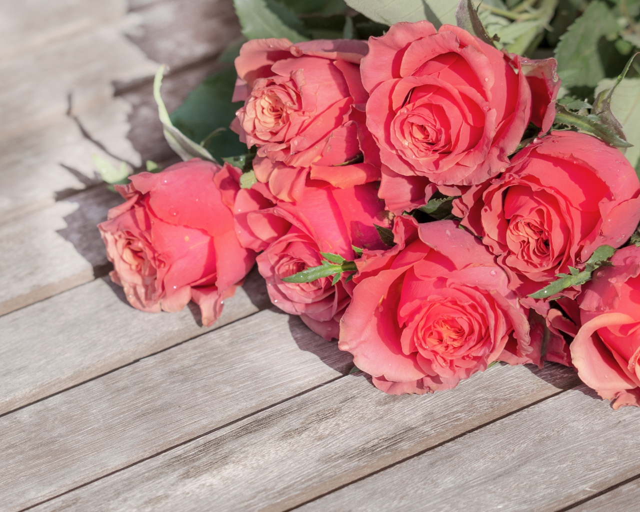 Букет розовых роз лежит на деревянной поверхности