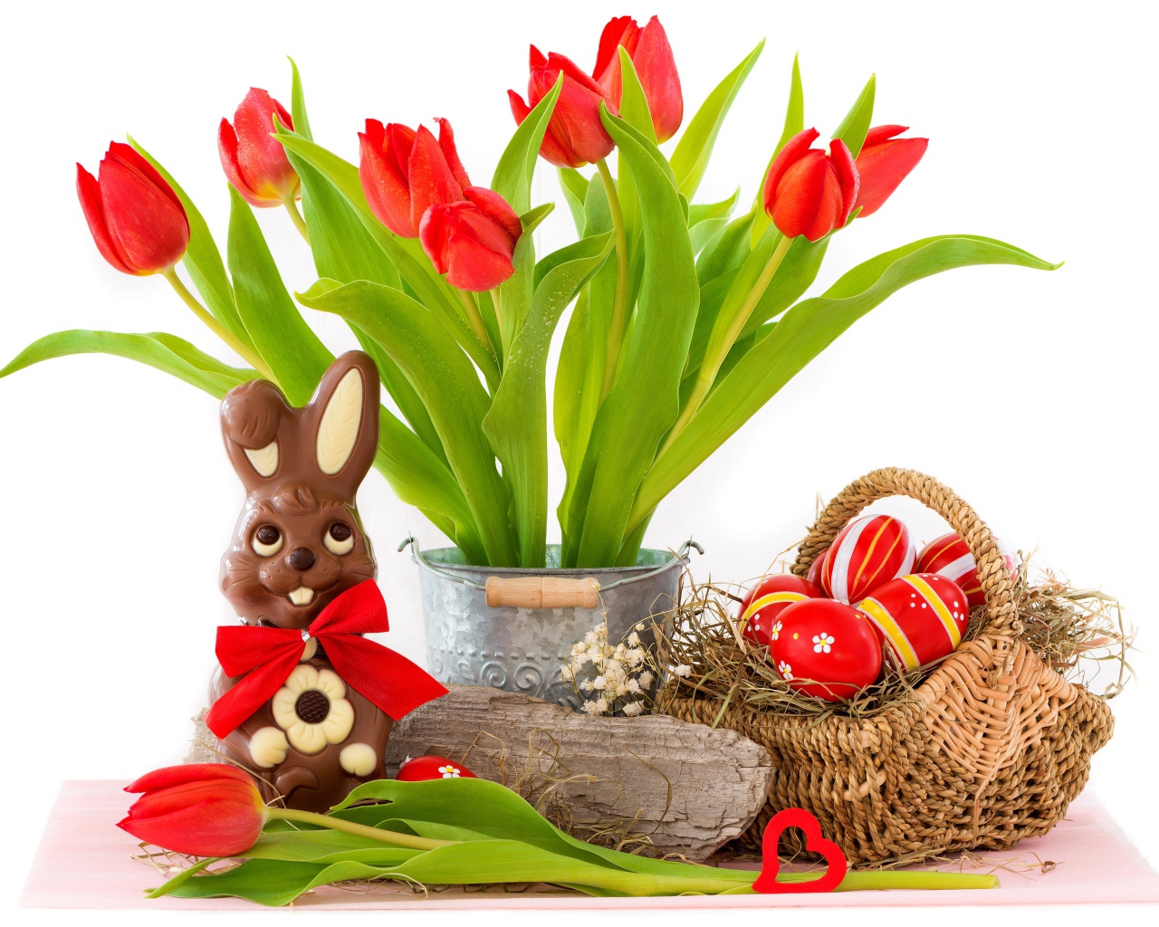 Букет красных тюльпанов на столе с шоколадным кроликом и крашеными яйцами на Пасху