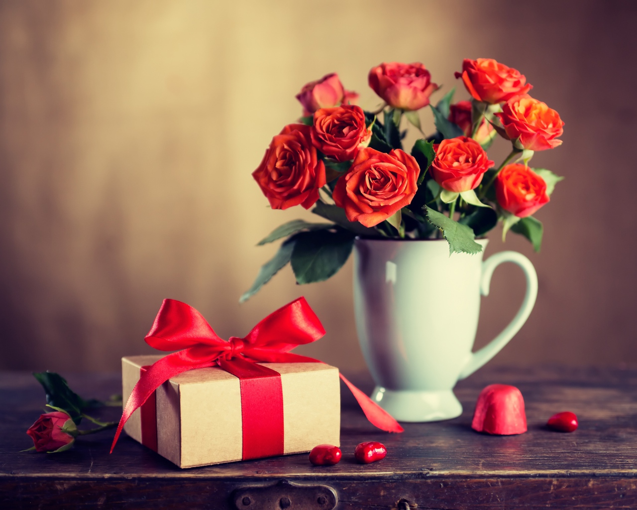 Букет роз в белой вазе с подарком на столе