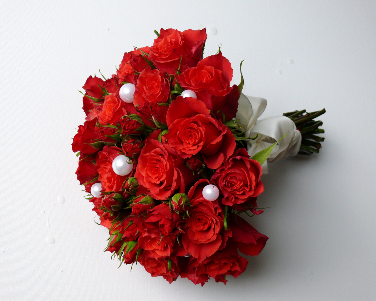 Красивый букет красных роз с жемчужными бусинами на сером фоне